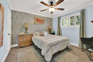 Carpeted bedroom with ornamental molding and ceiling fan