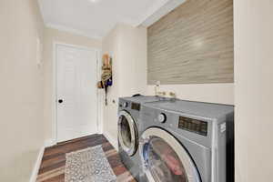 Laundry room featuring crown molding, washing machine and dryer, and dark hardwood / wood-style floors