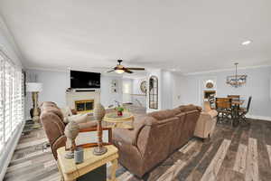 Living room featuring crown molding, ceiling fan with notable chandelier, and hardwood / wood-style floors