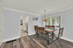 Dining room featuring an inviting chandelier, ornamental molding, and dark hardwood / wood-style floors