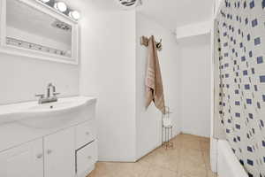 Bathroom featuring shower / bath combo with shower curtain, tile patterned floors, and vanity