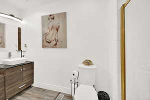 Bathroom featuring a shower with shower door, vanity, toilet, and hardwood / wood-style flooring