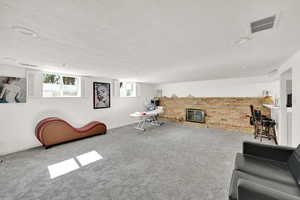 Carpeted living room with a textured ceiling and a brick fireplace