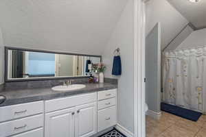 Bathroom featuring vanity, a textured ceiling, a shower with shower curtain, toilet, and tile patterned floors