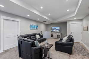 Living room with a tray ceiling and light carpet