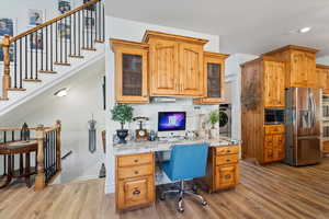 Office area featuring light wood-type flooring and built in desk, and granite countertops.