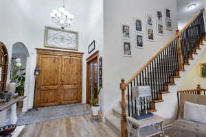 Foyer with a chandelier, light hardwood / wood-style floors, and a high ceiling