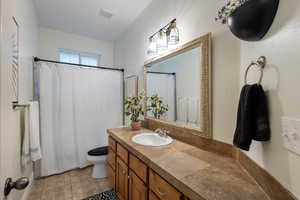 Bathroom featuring a shower with shower curtain, tile patterned floors, vanity, and toilet