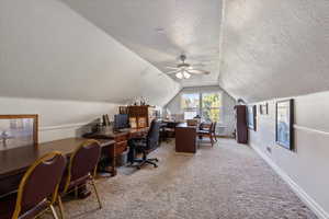 Office space with carpet floors, a textured ceiling, vaulted ceiling, and ceiling fan