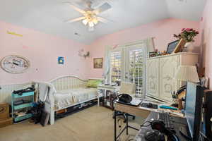 Carpeted bedroom with ceiling fan and vaulted ceiling