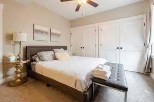 Carpeted bedroom featuring ceiling fan and two closets