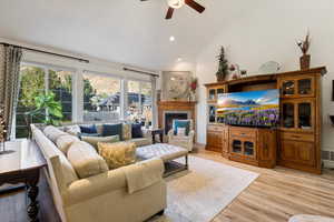 Living room with high vaulted ceiling, ceiling fan, light hardwood / wood-style flooring, and a wealth of natural light