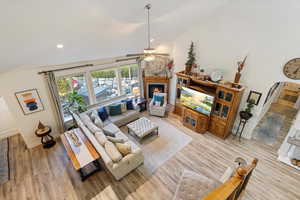 Living room featuring lofted ceiling, ceiling fan, and light hardwood / wood-style flooring