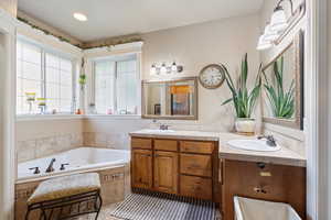 Master Bathroom with vanity, and travertine stone along bathtub, shower and countertops, and tile floors.