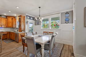 Dining space with an inviting chandelier, Custom cabinetry, light hardwood / wood-style floors, and sink, and granite countertops.