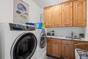 Laundry area featuring washer and clothes dryer, sink, and cabinets