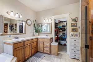 Master Bathroom with vanity, a washtub, and travertine stone along bathtub, shower and countertops.