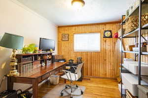 Home office with wood-type flooring, wooden walls, and crown molding