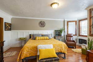 Bedroom featuring wood-type flooring, a textured ceiling, and crown molding