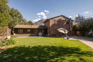 Rear view of property with a lawn and a patio area