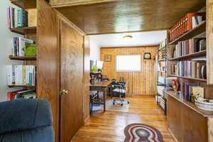 Office with wooden walls, light hardwood / wood-style flooring, and ornamental molding