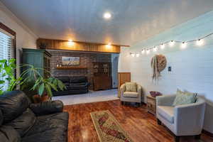 Living room with a textured ceiling, wooden walls, ornamental molding, and dark hardwood / wood-style flooring