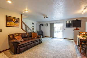 Living room with a wood stove, a textured ceiling, track lighting, and light tile patterned flooring