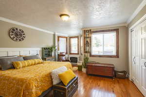 Bedroom with ornamental molding, wood-type flooring, a closet, and a textured ceiling