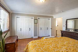 Bedroom featuring light hardwood / wood-style flooring, two closets, a textured ceiling, and crown molding