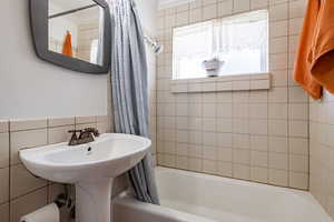 Bathroom with shower / bath combination with curtain, tile walls, and ornamental molding