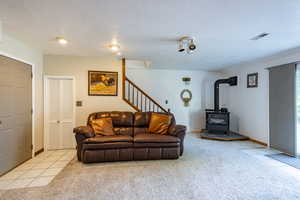 Carpeted living room featuring a textured ceiling and a wood stove