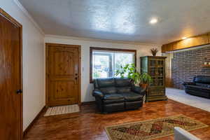 Living room with a textured ceiling, ornamental molding, and dark wood-type flooring