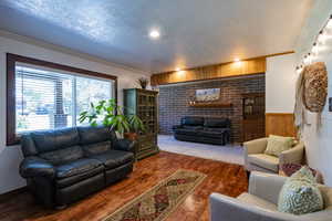 Living room featuring a textured ceiling, ornamental molding, wood walls, and dark hardwood / wood-style floors