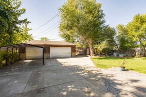 View of front of house with a carport, a garage, and a front yard