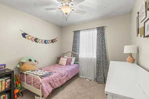 Carpeted bedroom with ceiling fan and a textured ceiling