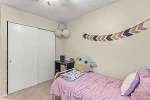 Carpeted bedroom featuring a textured ceiling, ceiling fan, and a closet