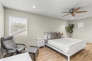 Bedroom with multiple windows, light wood-type flooring, and ceiling fan