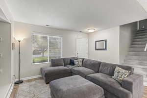 Living room with a textured ceiling and light hardwood / wood-style floors