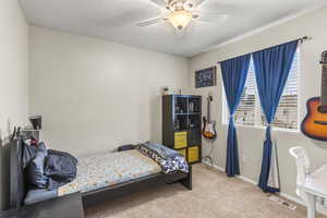 Carpeted bedroom featuring a textured ceiling and ceiling fan