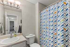 Bathroom with a shower with curtain, vanity, toilet, and a textured ceiling