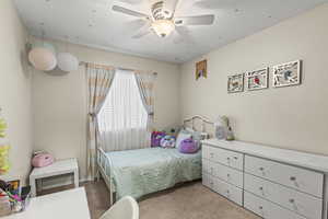 Bedroom with a textured ceiling, ceiling fan, and light colored carpet