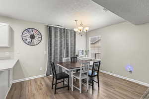 Dining area with a notable chandelier, light hardwood / wood-style floors, and a textured ceiling