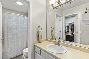 Bathroom featuring walk in shower, vanity, and toilet