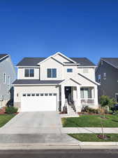 View of front of property with covered porch, a front yard, and a garage