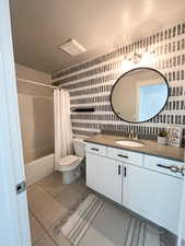 Full bathroom featuring tile patterned flooring, shower / bath combo, a textured ceiling, vanity, and toilet