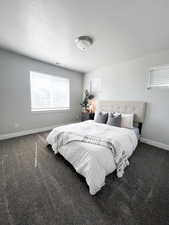 Bedroom featuring dark carpet and a textured ceiling