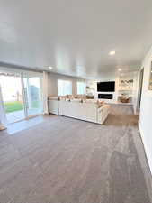 Unfurnished living room with built in shelves, light colored carpet, and a textured ceiling