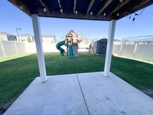 View of patio with a storage shed and a playground