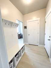 Mudroom with a textured ceiling and light wood-type flooring