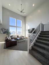 Living room featuring light wood-type flooring, a high ceiling, and ceiling fan